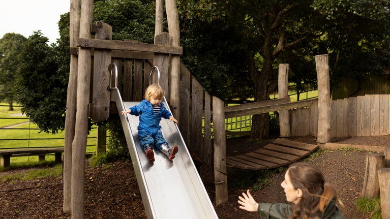 A child slides down the slide in the play area at Killerton, Devon